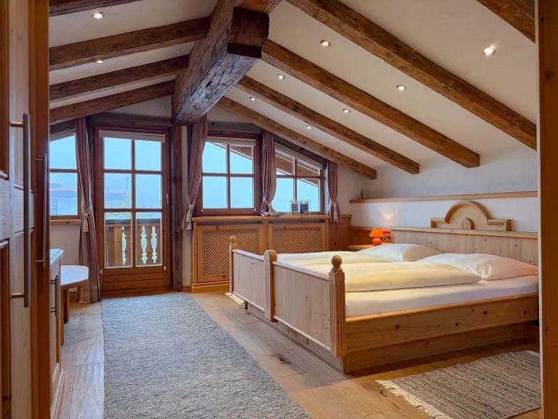 Schlafbereich der Suite Rettenstein mit Doppelbett, Altholzbalken und eigenem Balkon
